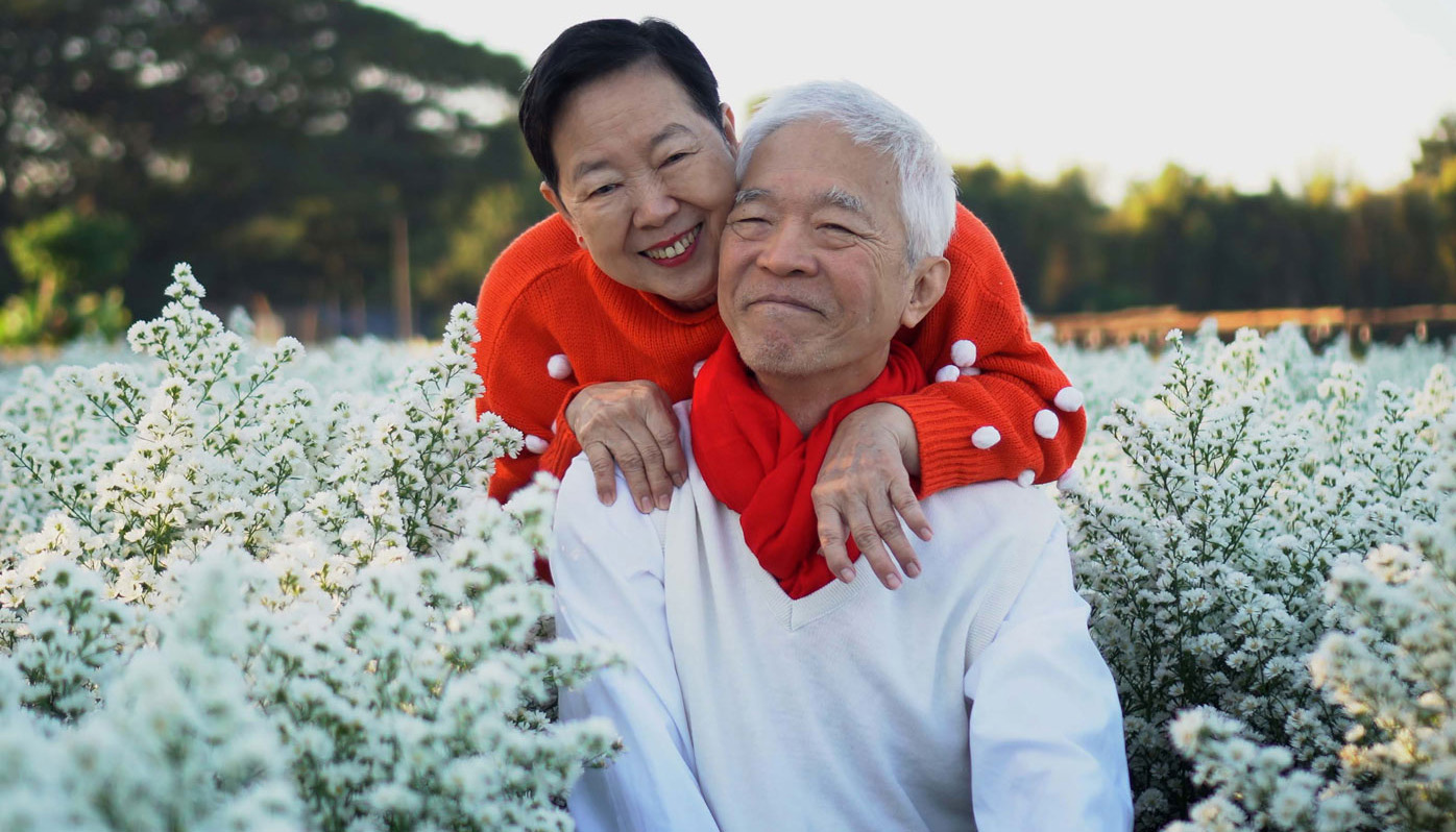 An asian couple smile amid a walk through a cotton field