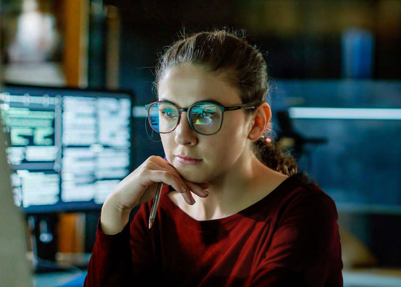 A woman gazes intently at code.