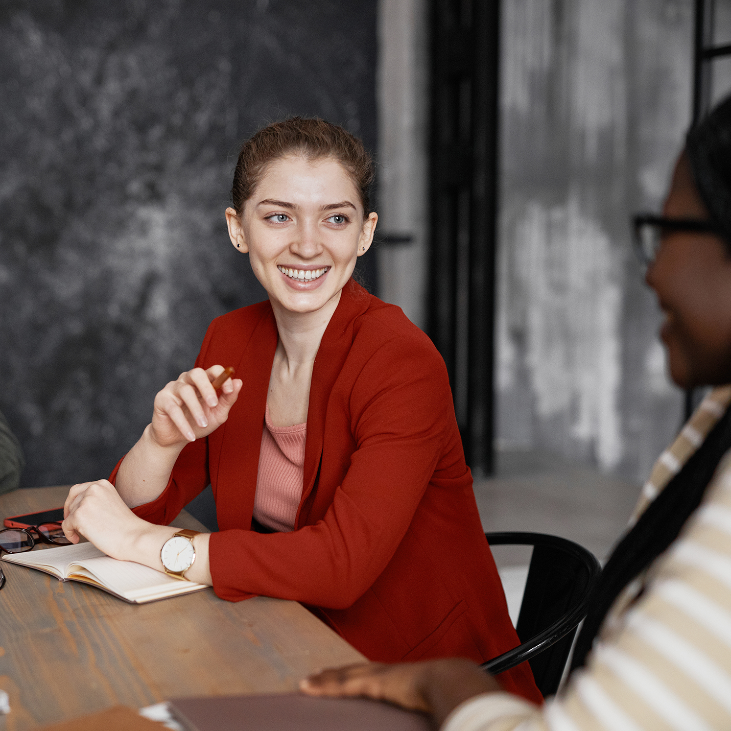 Woman in red sweater smiling in a meeting