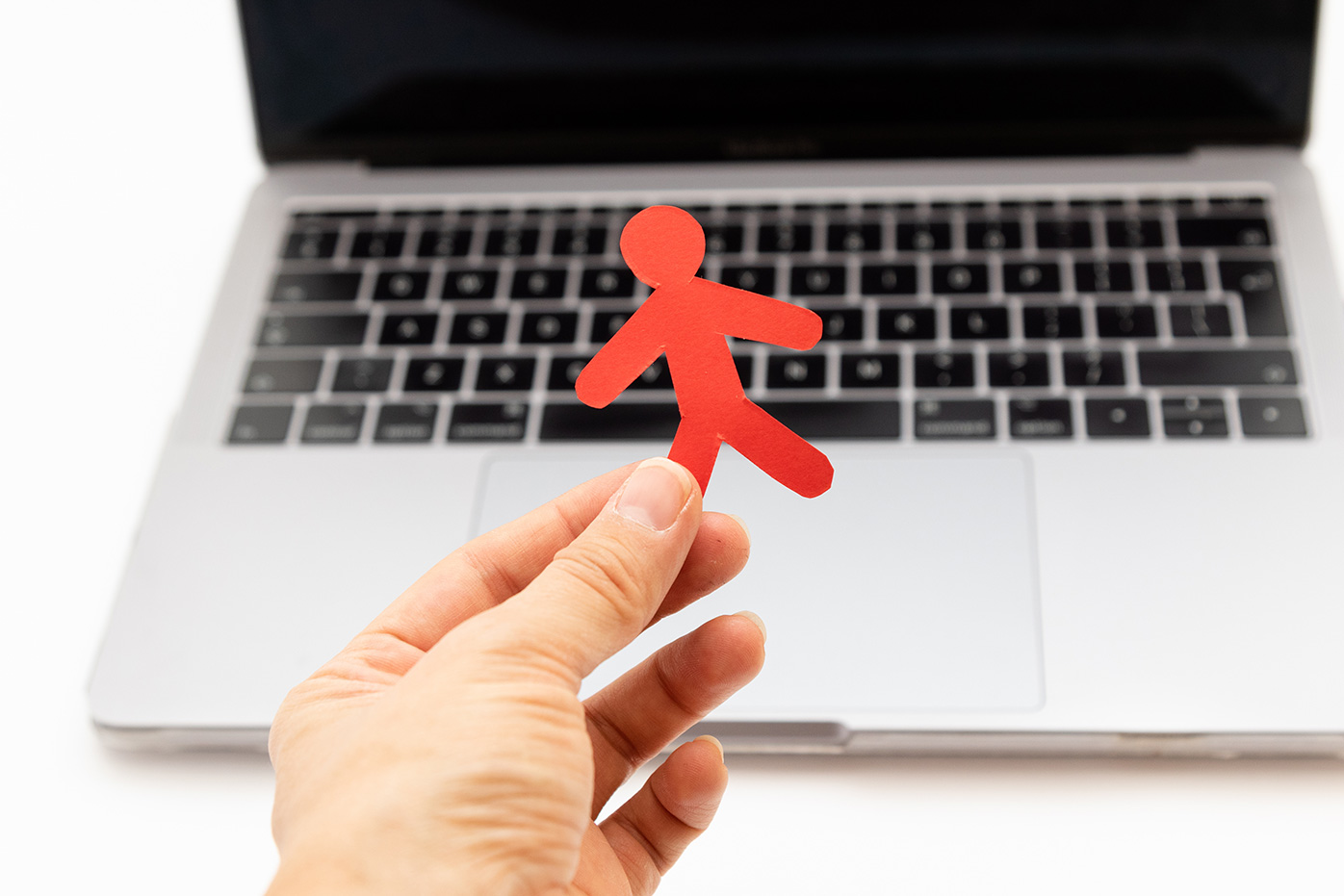 A paper cutout of a person held over a laptop