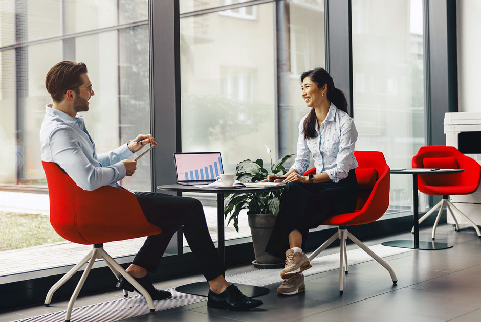 A pair of colleagues meet over a coffee and explore actuarial results on a laptop