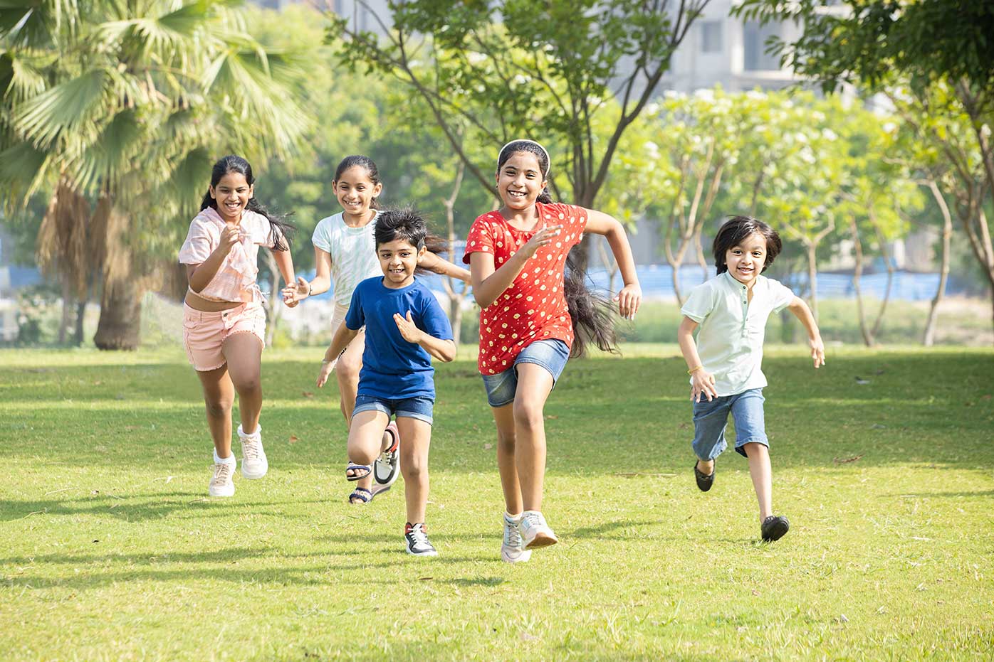 Five kids running across a grass field