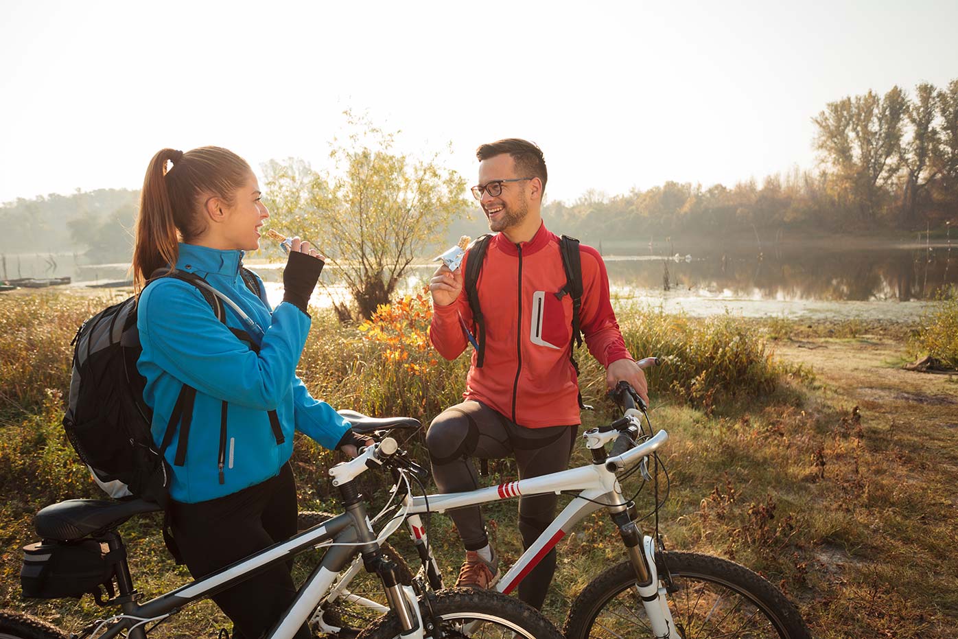 A man and a woman on bikes near a lake