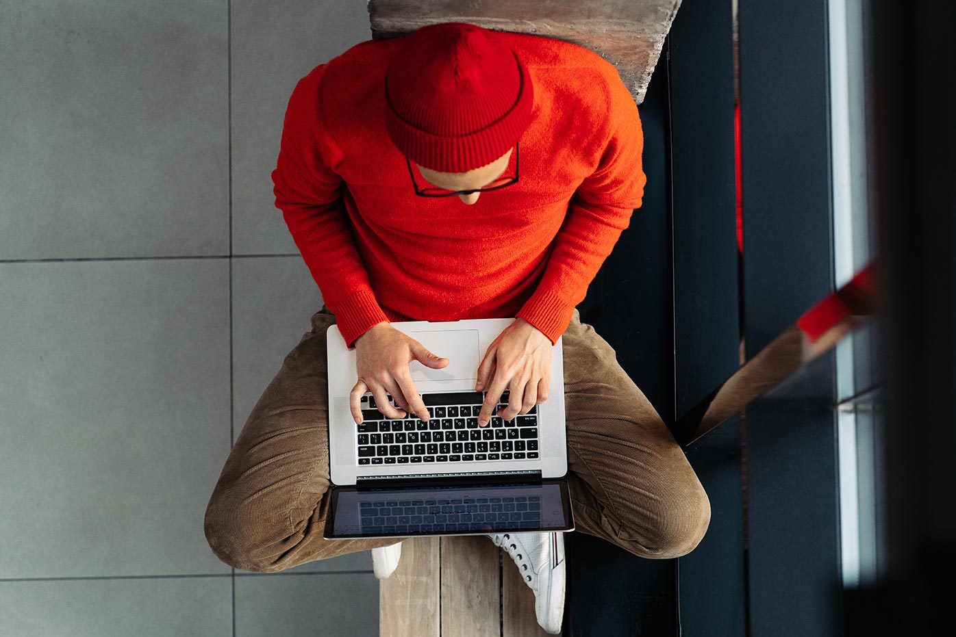 Birdseye view of man in red hat and red shirt working on a laptop