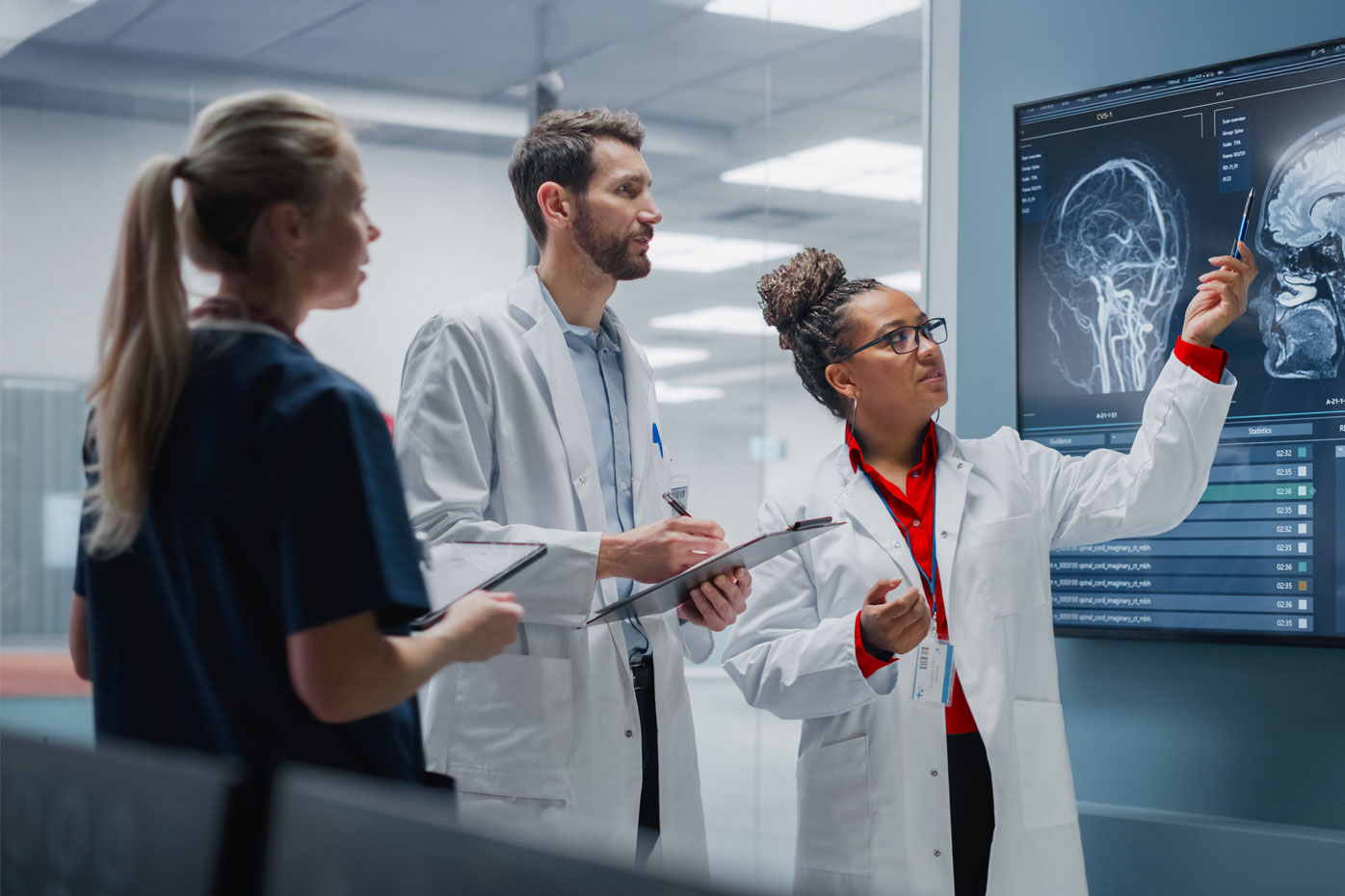 Three medical professionals review a brain scan