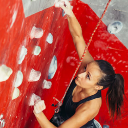 A female climber scales a climbing wall