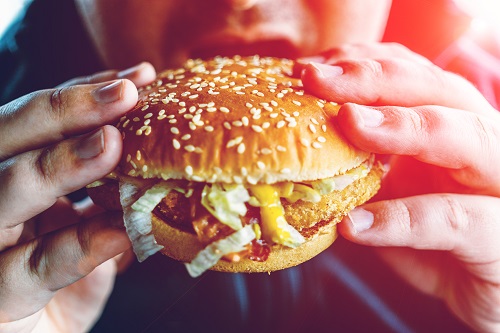 Individual taking a bite out of a burger