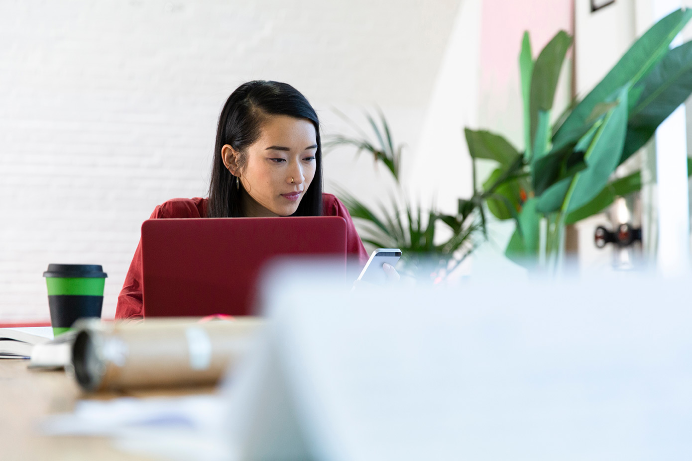 Woman on red laptop in foreground while also on the phone