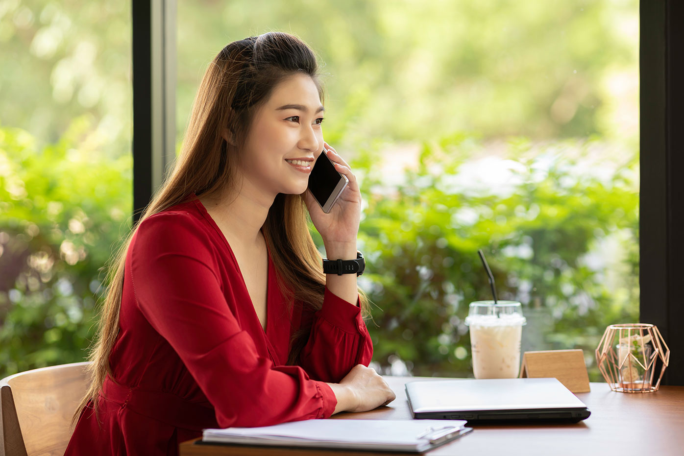 Woman in a red dress sitting at a table talking on her phone