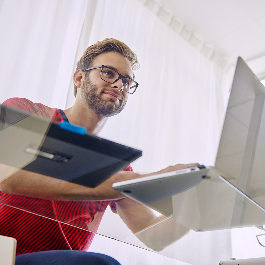 Younger man on computer through glass desk