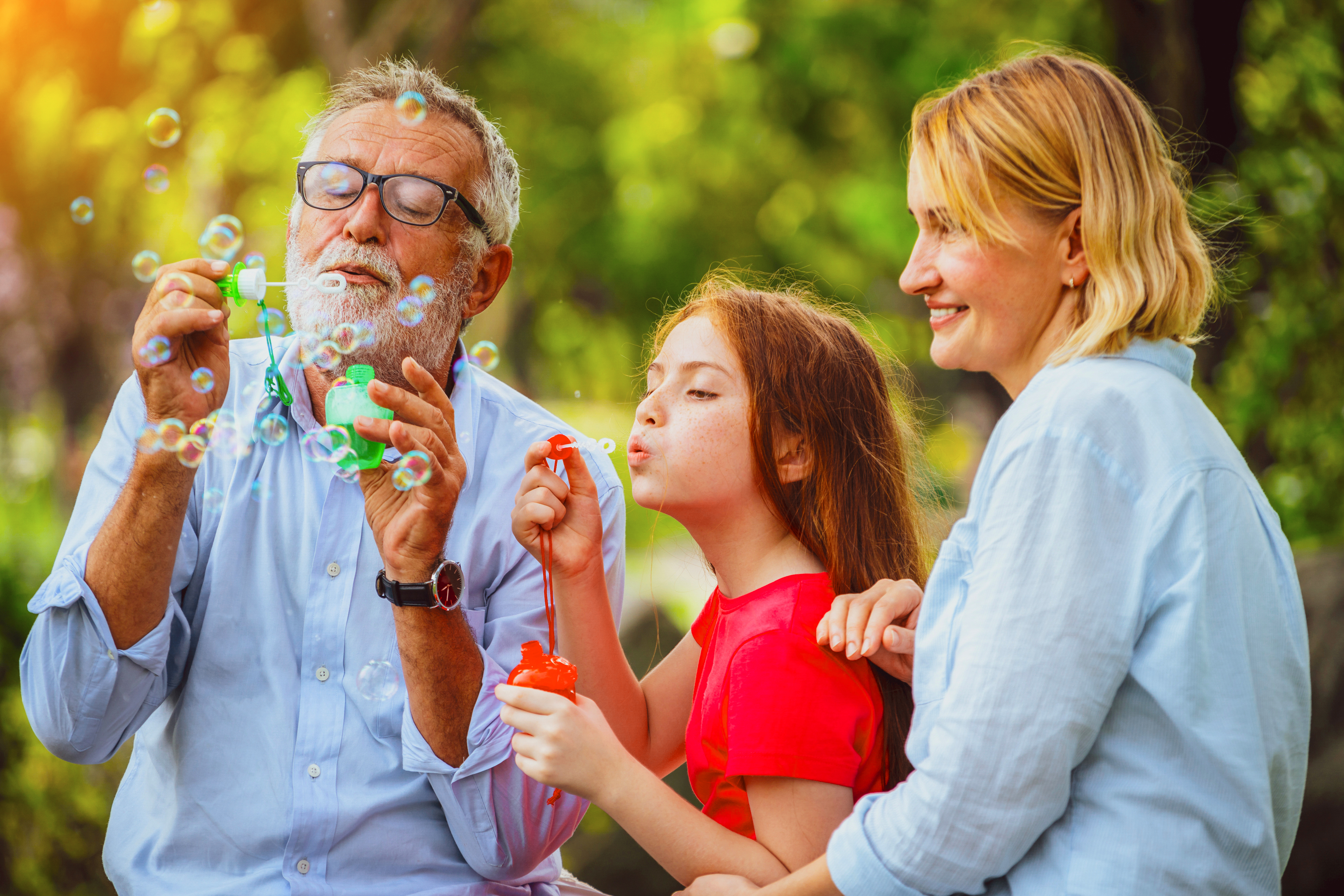 Grandfather, daughter, and grandchild blowing bubbles A grandfather blowing bubbles with his grandchild and daughter