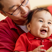 A dad in China cradles his laughing baby