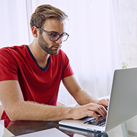 Man in a red shirt working on a laptop