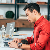 Man in red shirt working on a laptop