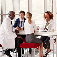 Four medical people sitting at a table with red chairs