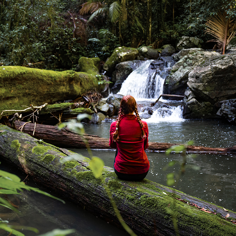 Woman sitting by a waterfall reflecting on life